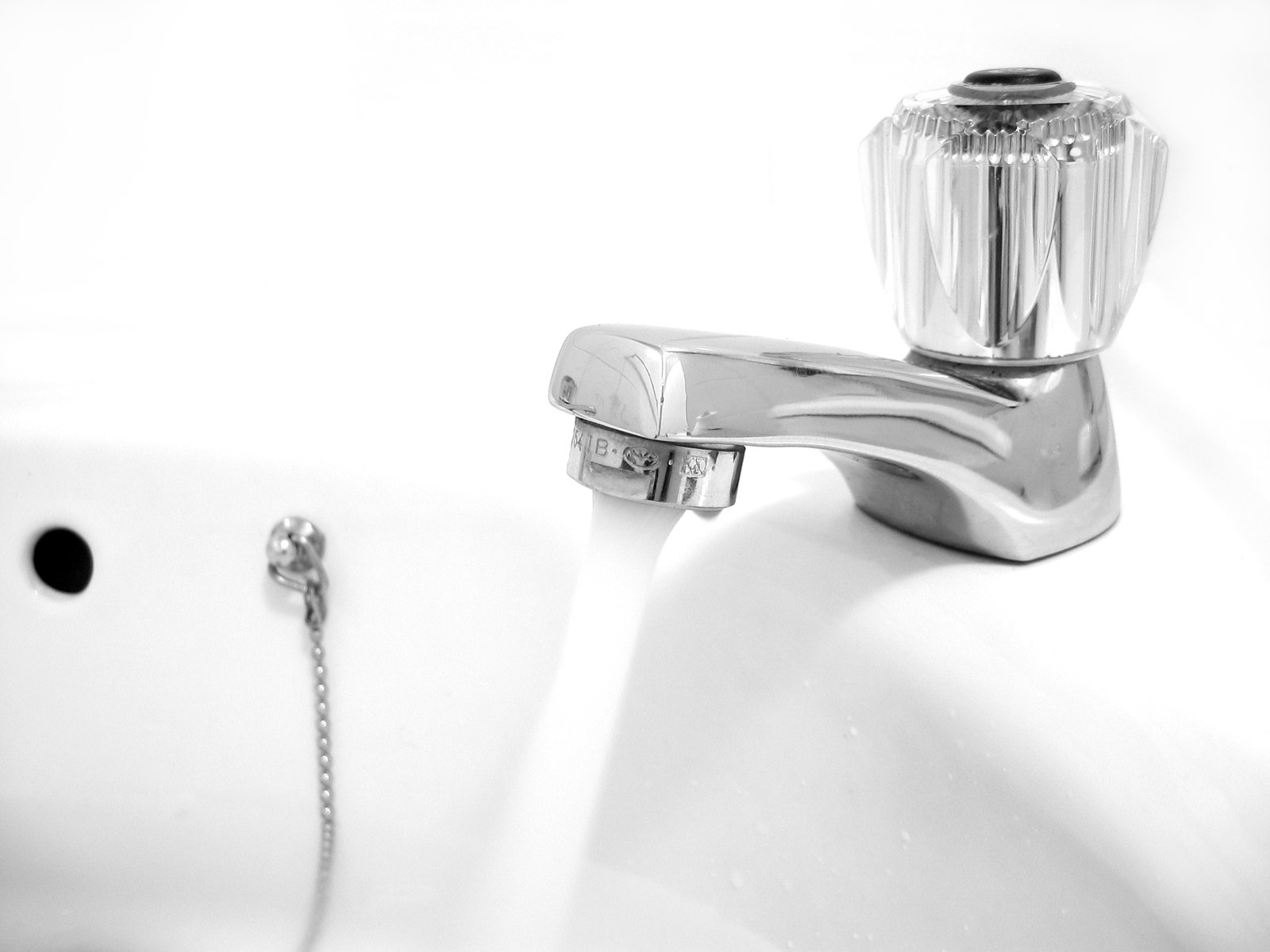 Chrome tap running water into a clean white basin