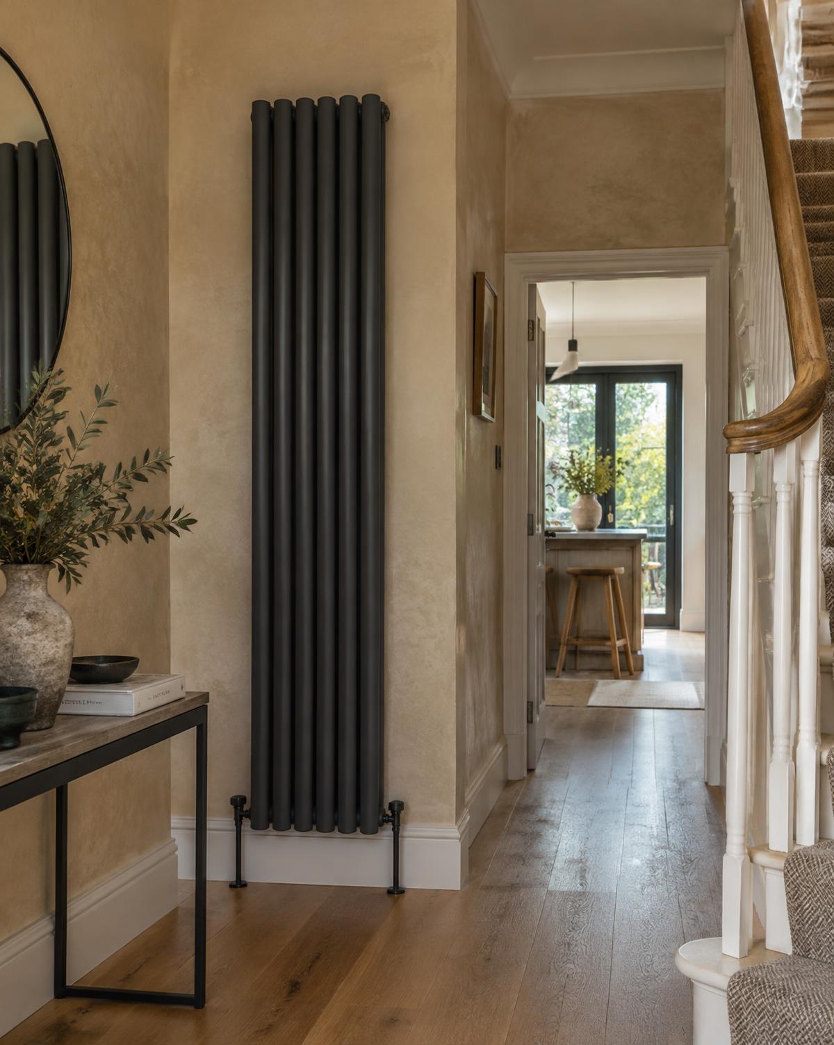 Tall anthracite column radiator in an elegant hallway with oak flooring